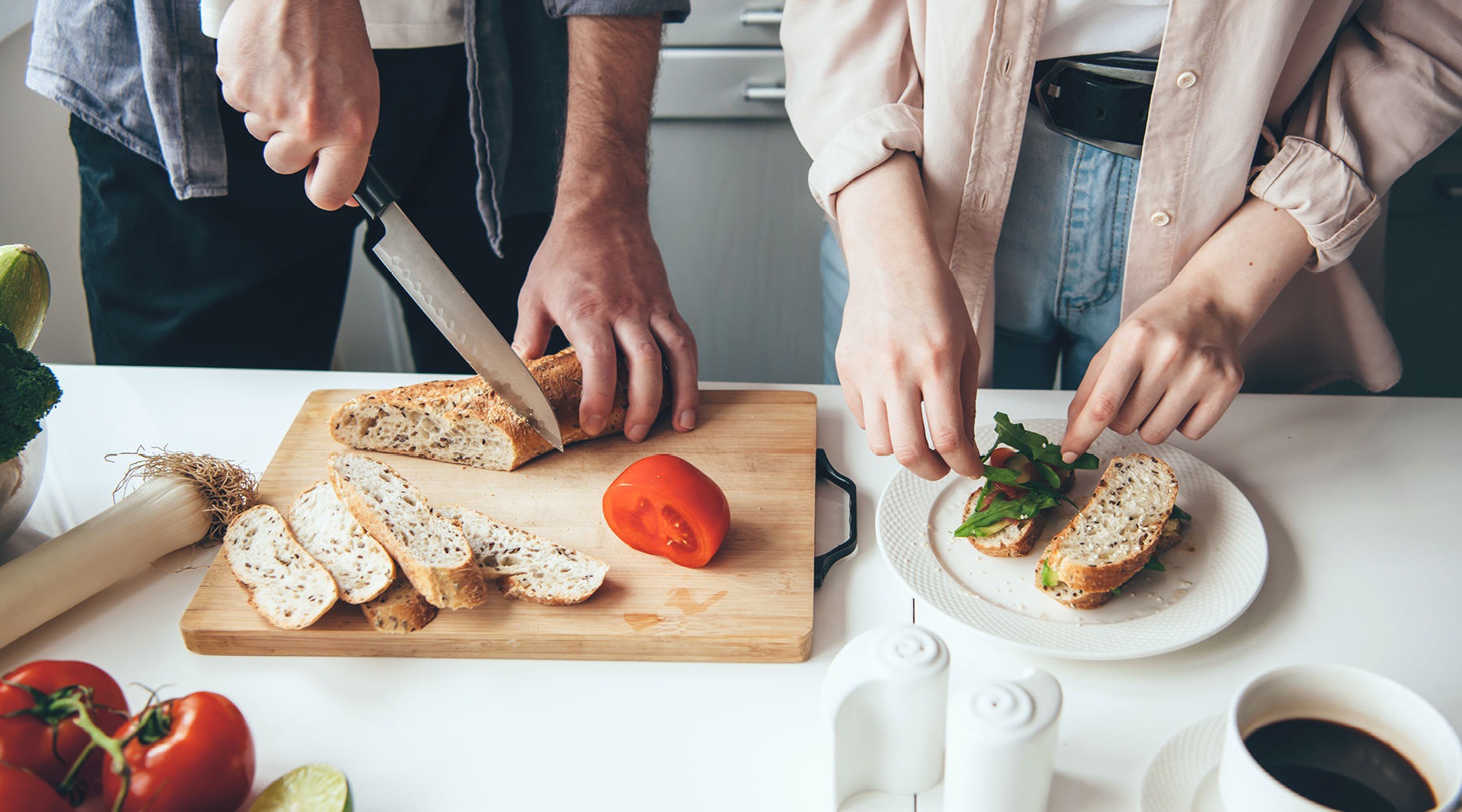 man and woman prepare food on kitchen island
